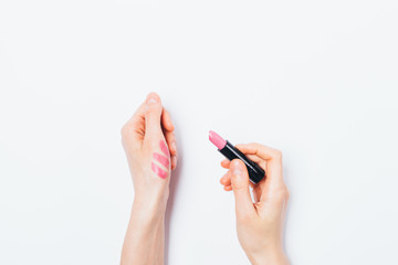 Woman's hands apply test sample of pink lipstick