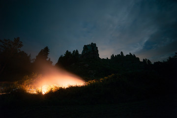 Beautiful landscape of Huge mountain rocks in the night with flares of lights in the grass