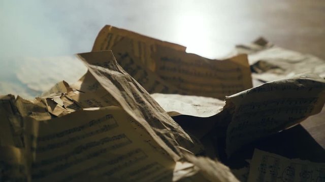 Vintage sheets with notes are burning in smoke in slow motion