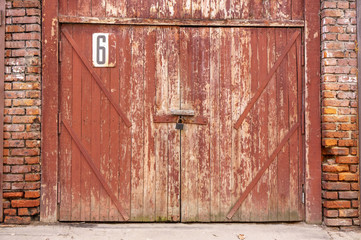 Old garage door in a white concrete wall. Gates made of wood painted with cracked green paint