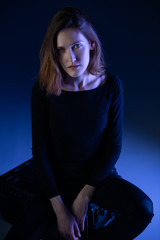 Fashion model. Portrait of young woman posing in studio with blue light. Beautiful caucasian girl