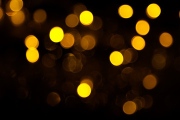 Abstract gold bokeh on black background. Defocused yellow lights, abstract texture
