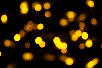 Abstract gold bokeh on black background. Defocused yellow lights, abstract texture