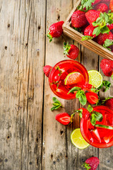 Homemade strawberry lemonade with lime and mint, rustic wooden background copy space