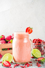 Healthy blended drink. Organic diet smoothie with lime, strawberry and goji berries, wooden background copy space