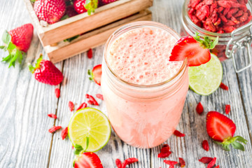 Healthy blended drink. Organic diet smoothie with lime, strawberry and goji berries, wooden...