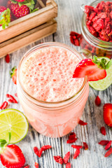 Healthy blended drink. Organic diet smoothie with lime, strawberry and goji berries, wooden background copy space