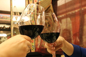 A glass of red wine.Toasting with wine glasses. Two wine glasses clink at the party, close-up view of friends clinking glasses of red wine