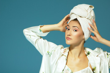 Cheerful attractive funny teen girl with towel on her head, over blue background. Morning beautiful young woman