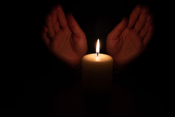Hands in the dark over burning candles