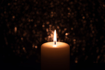 burning candle in the dark on a brilliant background