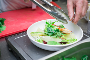 The concept of healthy and healthy food, Mediterranean cuisine, Italian recipe, the chef prepares a salad of fresh vegetables and shrimp