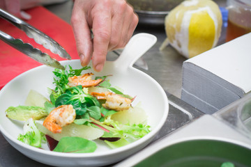 The concept of healthy and healthy food, Mediterranean cuisine, Italian recipe, the chef prepares a salad of fresh vegetables and shrimp