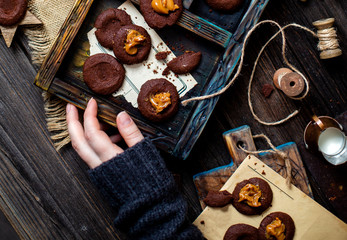 Overhead shot of homemade chocolate tasty cookies with caramel or condensed milk on dark blue wooden board with copper cup with caramel on rustic table