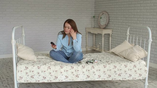 A sad woman with type 1 diabetes is sitting on the bed at home with a glucometer in her hands, she is upset by the high rate of glucose in the blood. Hyperglycemia.