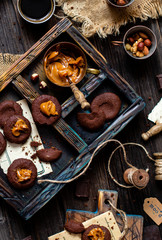 Fototapeta na wymiar Overhead shot of homemade chocolate tasty cookies with caramel or condensed milk on dark blue wooden board with copper cup with caramel on rustic table