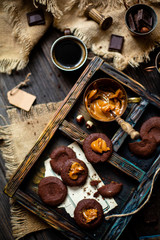 Overhead shot of homemade chocolate tasty cookies with caramel or condensed milk on dark blue wooden board with copper cup with caramel on rustic table