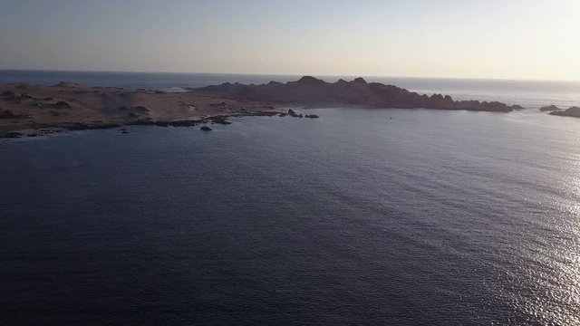 Las Tortolas beach aerial footage at Atacama Desert the sunset ray lights illuminate this amazing and idyllic beach in the middle of the desert, an arid awe landscape crashed by Pacific Ocean waters