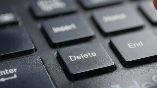 Finger pushing delete key on laptop keyboard