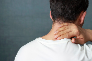 A man is massaging a sore neck, close-up, rear view.
