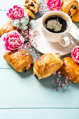Breakfast with mini fresh croissants bun with chocolate and coffee cup on blue turquoise background. Copy space.