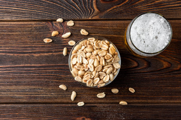 Beer with salted peanut on dark wooden background. 