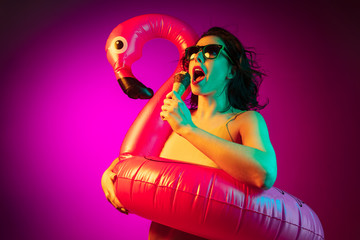 Happy young woman standing and smiling against pink background