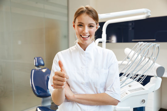 Image of beautiful happy woman doctor in medical dentist center showing thumb up