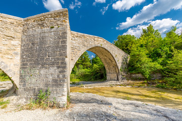 Old historical stone bridge over river on a summer day in south France