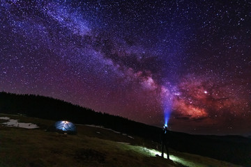 Space starry sky with galaxy Milky way on the background of a tourist with a tent in the Ukrainian Carpathian mountains