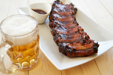 Grilled pork ribs with barbecue sauce and beer mug. View from above.