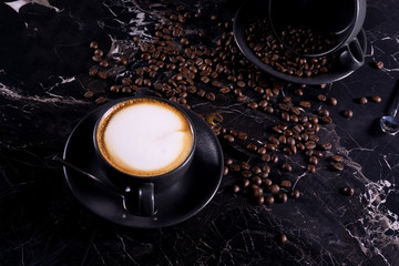 fresh flat white coffee on black marble table with coffee beans