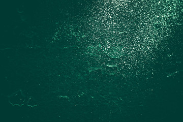 Vintage green background. Rough painted wall of emerald color. Imperfect plane of virid colored. Uneven old decorative toned backdrop of green tint. Texture of emerald hue. Ornamental stony surface.