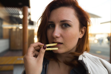 Fri potatoes close up face - Eating and enjoying - Young Woman eating in Fast Food Restaurant -...