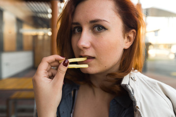 Fri potatoes close up face - Eating and enjoying - Young Woman eating in Fast Food Restaurant -...