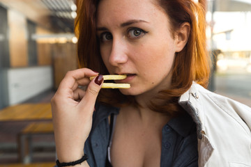 Fri potatoes close up face - Eating and enjoying - Young Woman eating in Fast Food Restaurant -...