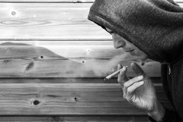 People with a rolled cigarette that spits smoke, shot in black and white. Man smoking marijuana or...