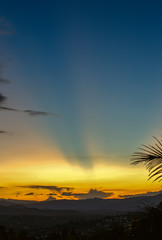 Multiple exposure of beams of light crossing the sky in an almost clear sunset over the central Andean mountains of Colombia.