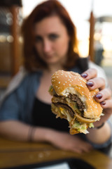 Hamburger close up - Young Woman eating in Fast Food Restaurant - Cheeseburger, medium fries and soda