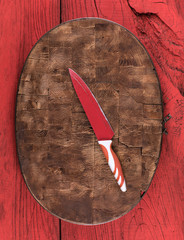 red table knife on a wooden kitchen board on a red wooden rustic table
