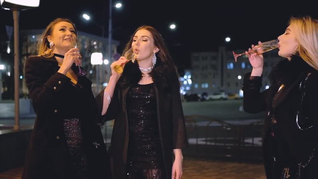 Girls night out party. Ladies drinking champagne on the street with night city lights, enjoying special day in the open air.