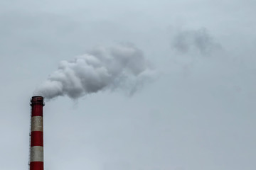 The pipe from which the smoke goes against the gray sky. The concept of air pollution, CO2, carbon...
