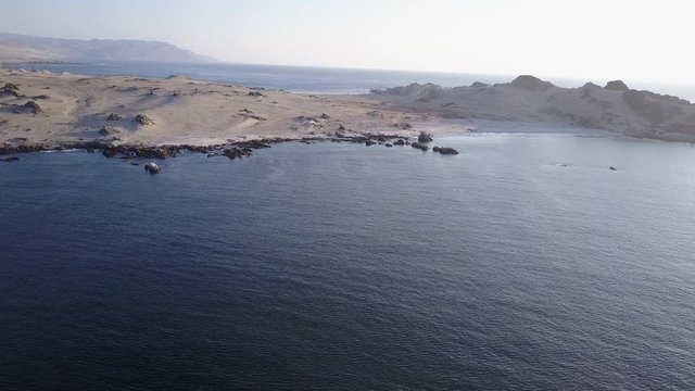 Las Tortolas beach aerial footage at Atacama Desert the sunset ray lights illuminate this amazing and idyllic beach in the middle of the desert, an arid awe landscape crashed by Pacific Ocean waters
