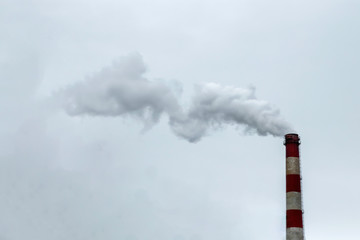 The pipe from which the smoke goes against the gray sky. The concept of air pollution, CO2, carbon dioxide gas, exhaust gases.