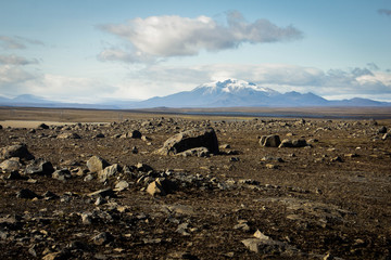 Stone desert, plain, emptiness, stones and mountains with snowy peaks in the background and blue sky with clouds above in Iceland. Alien landscape, dead land, dead and alien planet. Martian landscape. © Daniil