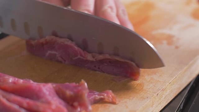 Cutting a filet mignon with a knife on a wooden board
