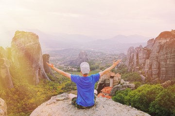 Naklejka premium Man traveler praying at sunset mountain summit enjoying aerial epic view raised hands Travel lifestyle success relaxation. Emotional vacations, outdoor adventure freedom, harmony with nature concept.