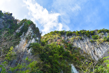 A rock formation's cliff with the blue sky above it as viewed from the ground. In El Nido, Palawan, Philippines.