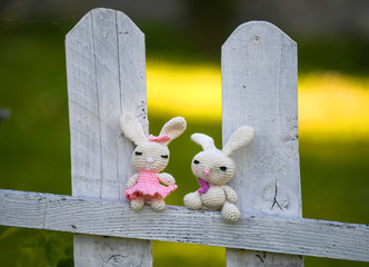 Fototapeta premium Handmade crochet rabbit toys on a white wooden fence