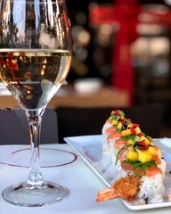 sushi with salmon and corn on a white plate and a glass of water